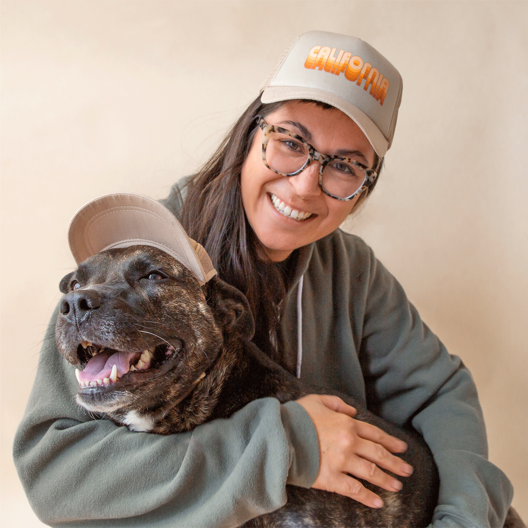 On a tan background is a model and a model dog wearing the puplids with orange gradient text across the front that reads, "California". 