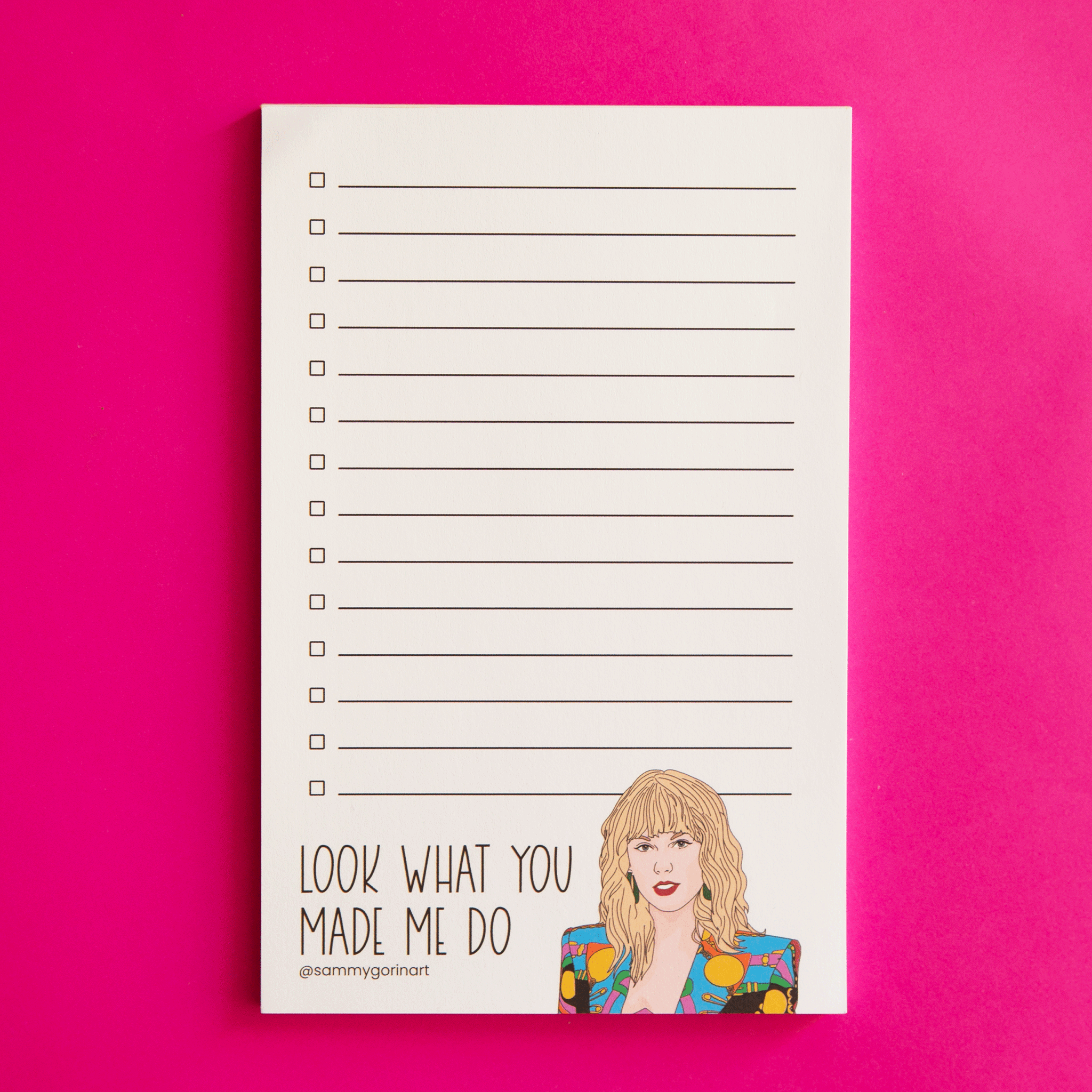 On a hot pink background is a white check list notepad with an illustration of Taylor Swift on the bottom with black text next to it that reads, &quot;Look What You Made Me Do&quot;.