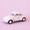On a pink background is an ivory VW bug toy. 