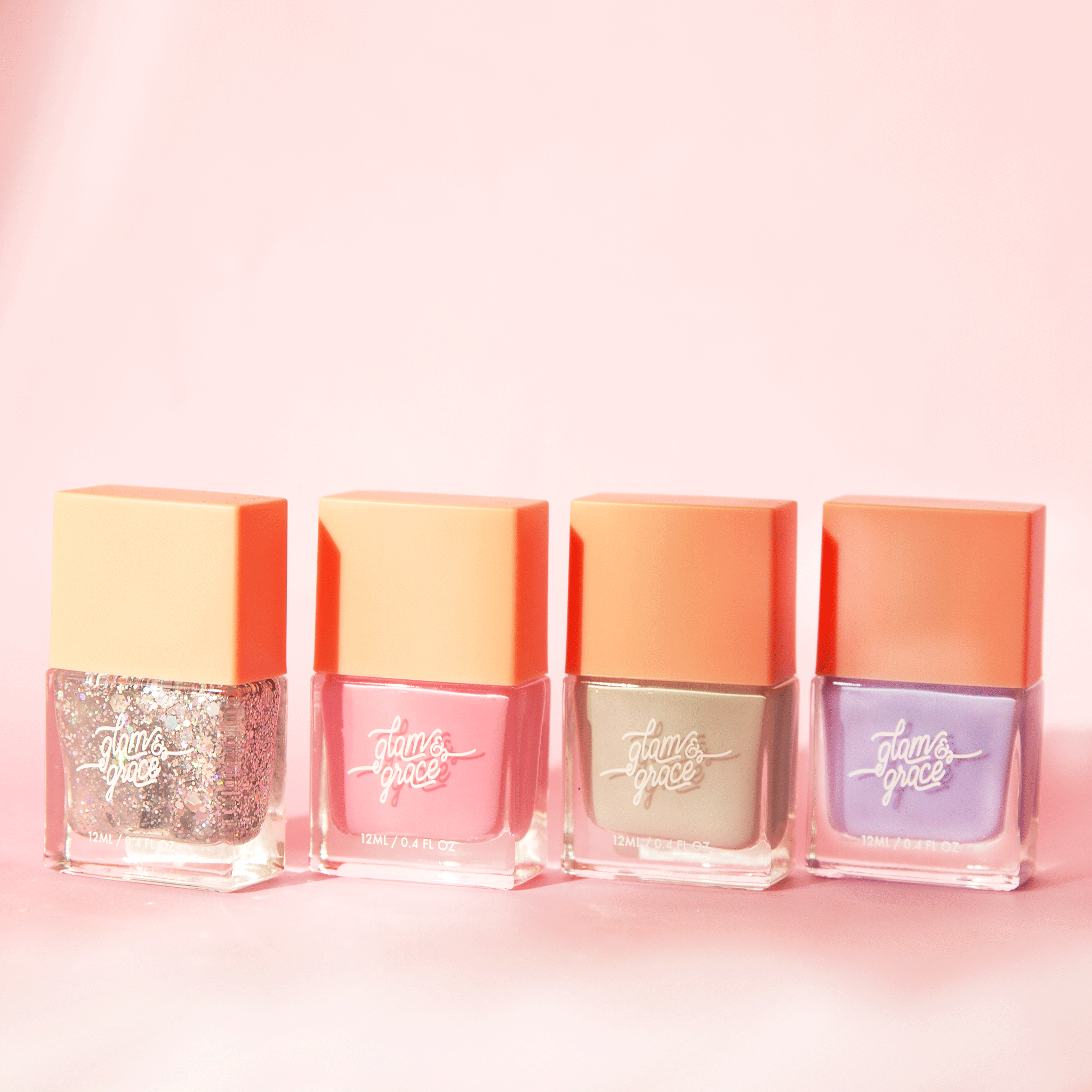 On a pink background is four rectangle bottles of nail polish next to one another. There is a silver sparkle, light pink, sage green and lilac purple color.