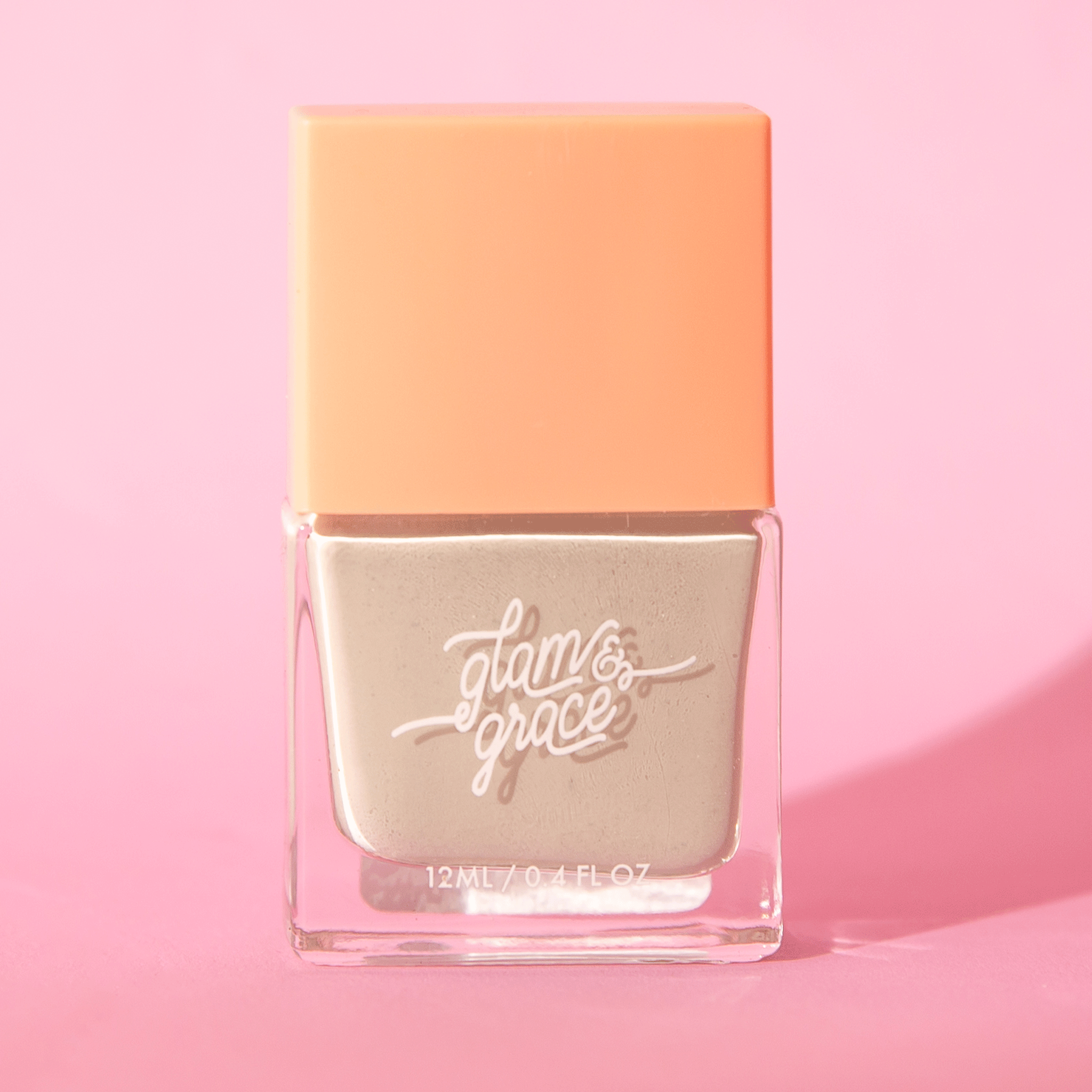 A sage green satin nail polish in a glass bottle with a peachy square lid.