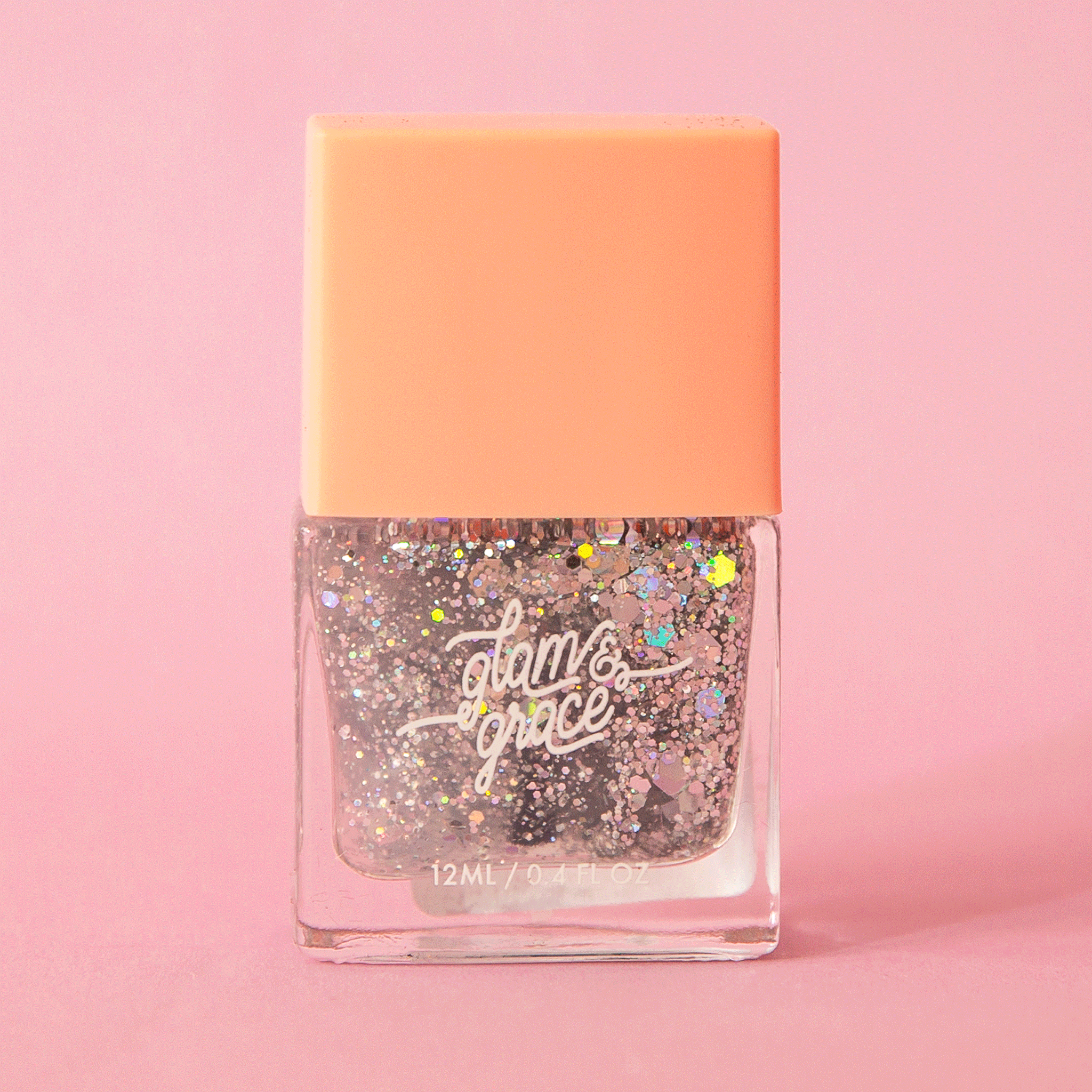 On a pink background is a rectangle bottle of silver sparkle nail polish with white text that reads, &quot;glam &amp; grace&quot; on the front.