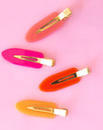 Four vibrant colored creaseless hair clips in orange, pink and yellow shades. 