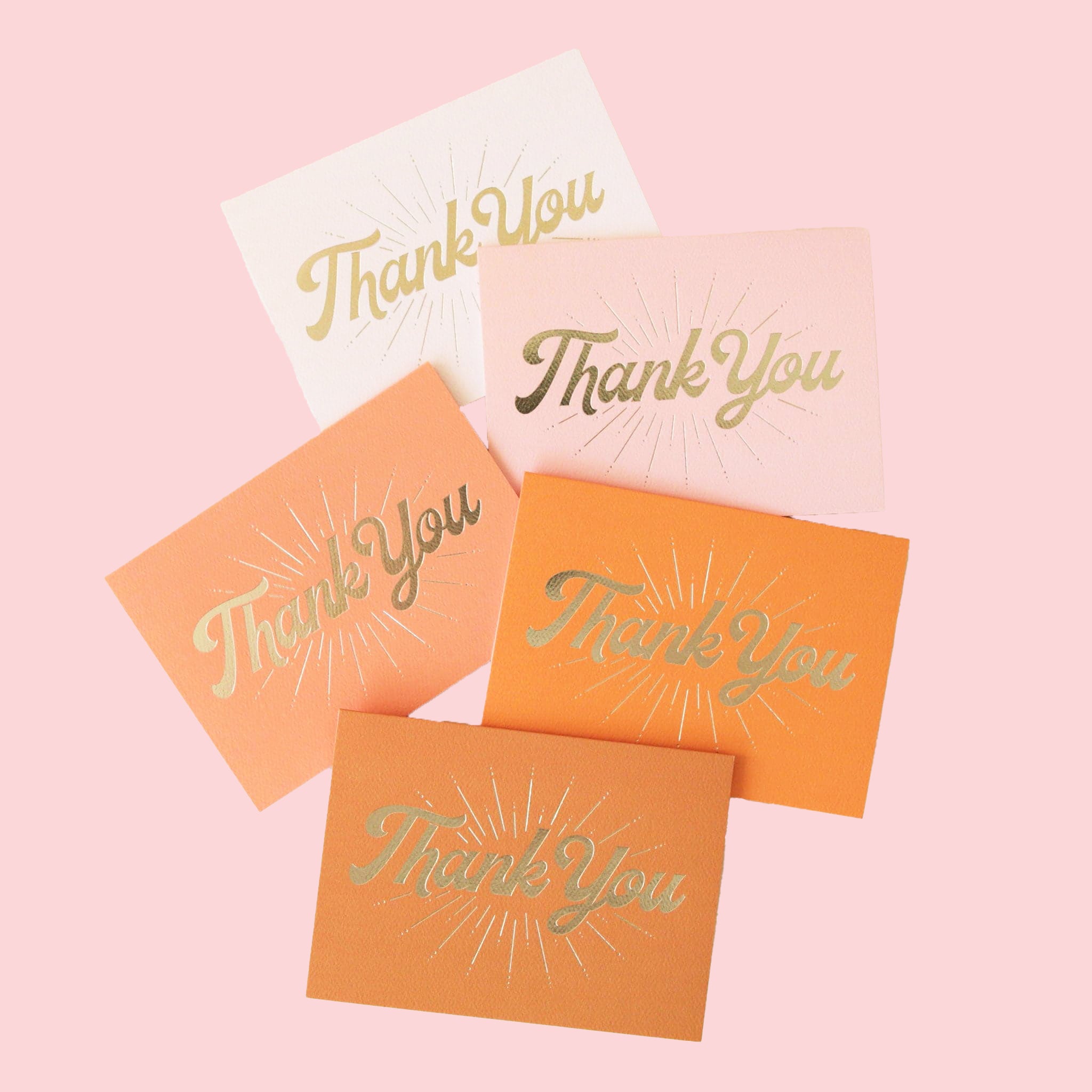 A pack of five different colored folded thank you cards with gold cursive font on the front that reads, "Thank You" along with gold line detailing. The colors range from ivory to light pink to terracotta.