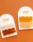 On an orange background is the cognac color way and pink mango version of the wavy hair clip sets.