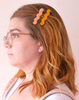 A model wearing the two shades of the wavy hair clips, one orange and one salmon pink. 