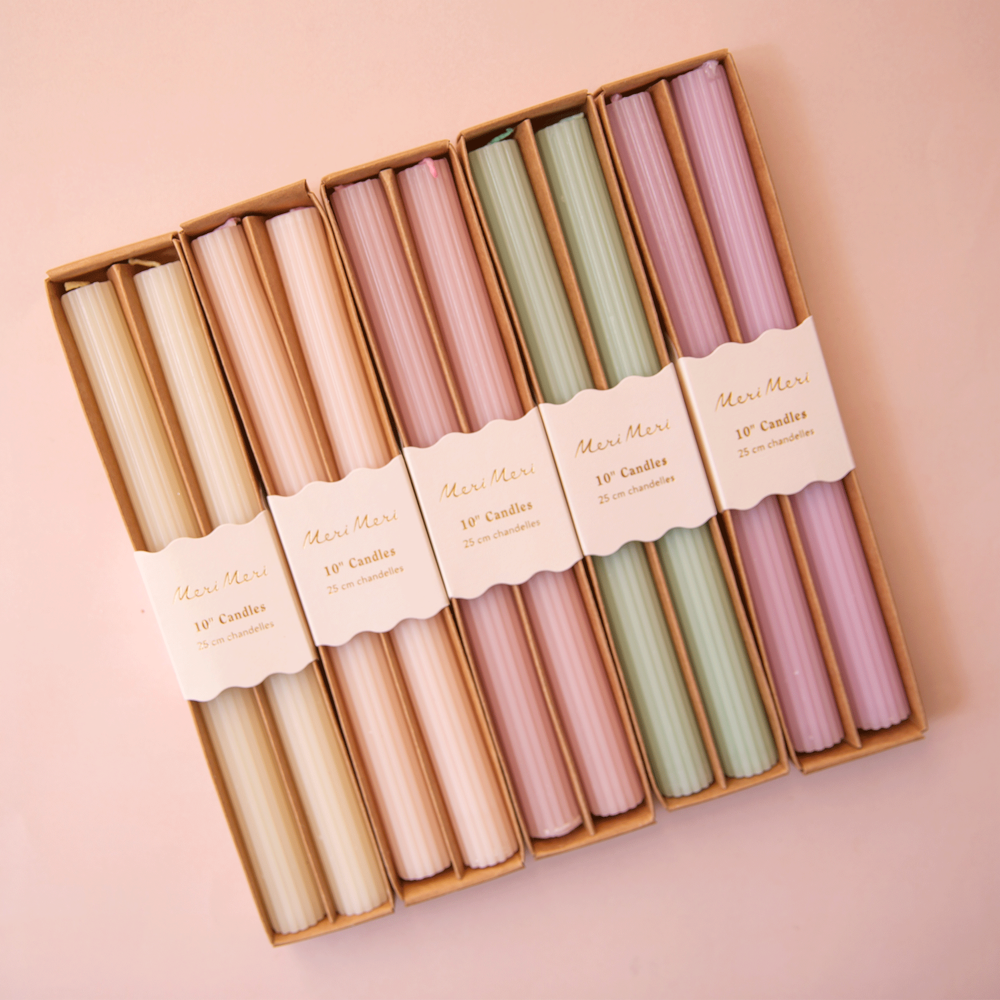 On a peachy background is all five color ways of the taper candles lined up next to one another. 