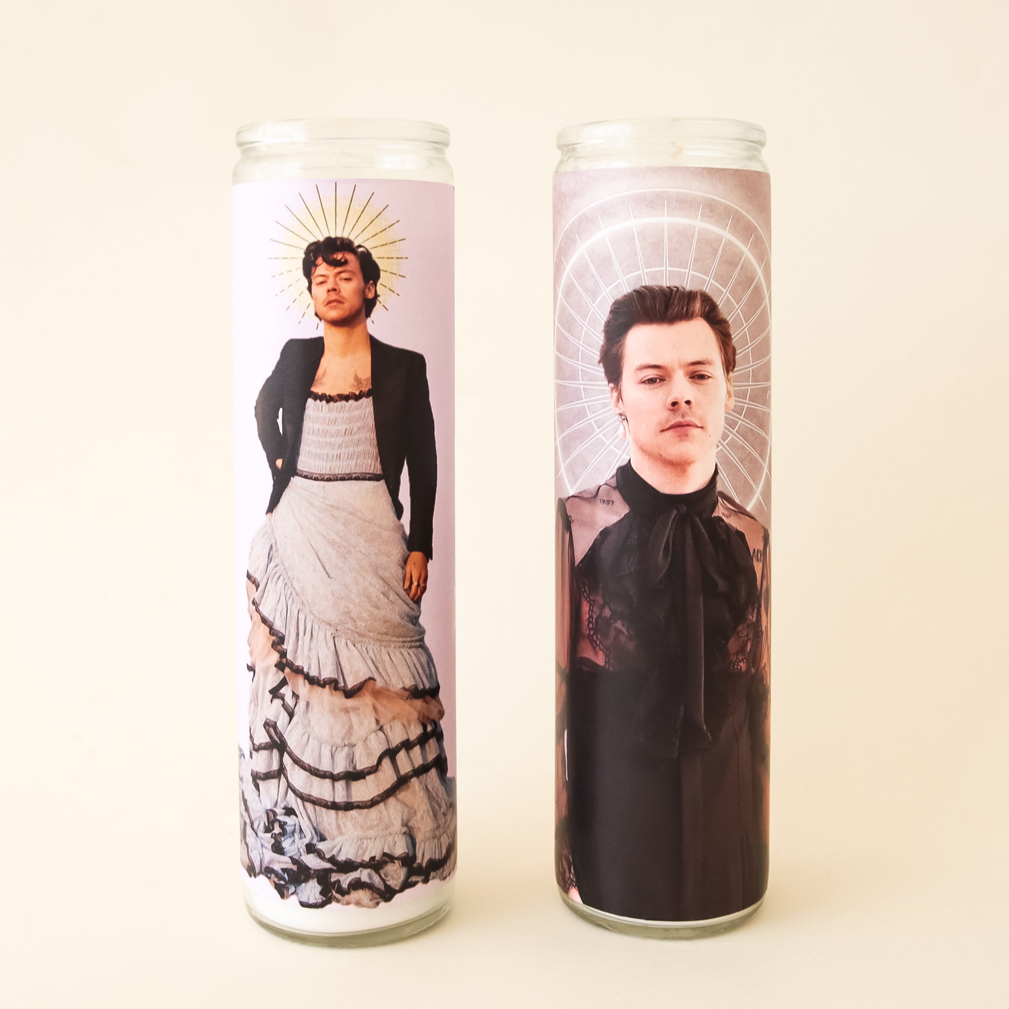 On a white background is a prayer candle with Harry Styles in a dress on the front photographed next to other available Harry Styles prayer candles on our site. 