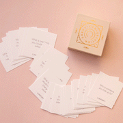 On a pink background is a box and white square cards that have conversation starting questions for your family to discuss. 