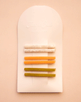 On a white packaging is six bobby pin clips in three different colors. From top to bottom is an ivory shell shade, mango orange, and olive green shade.