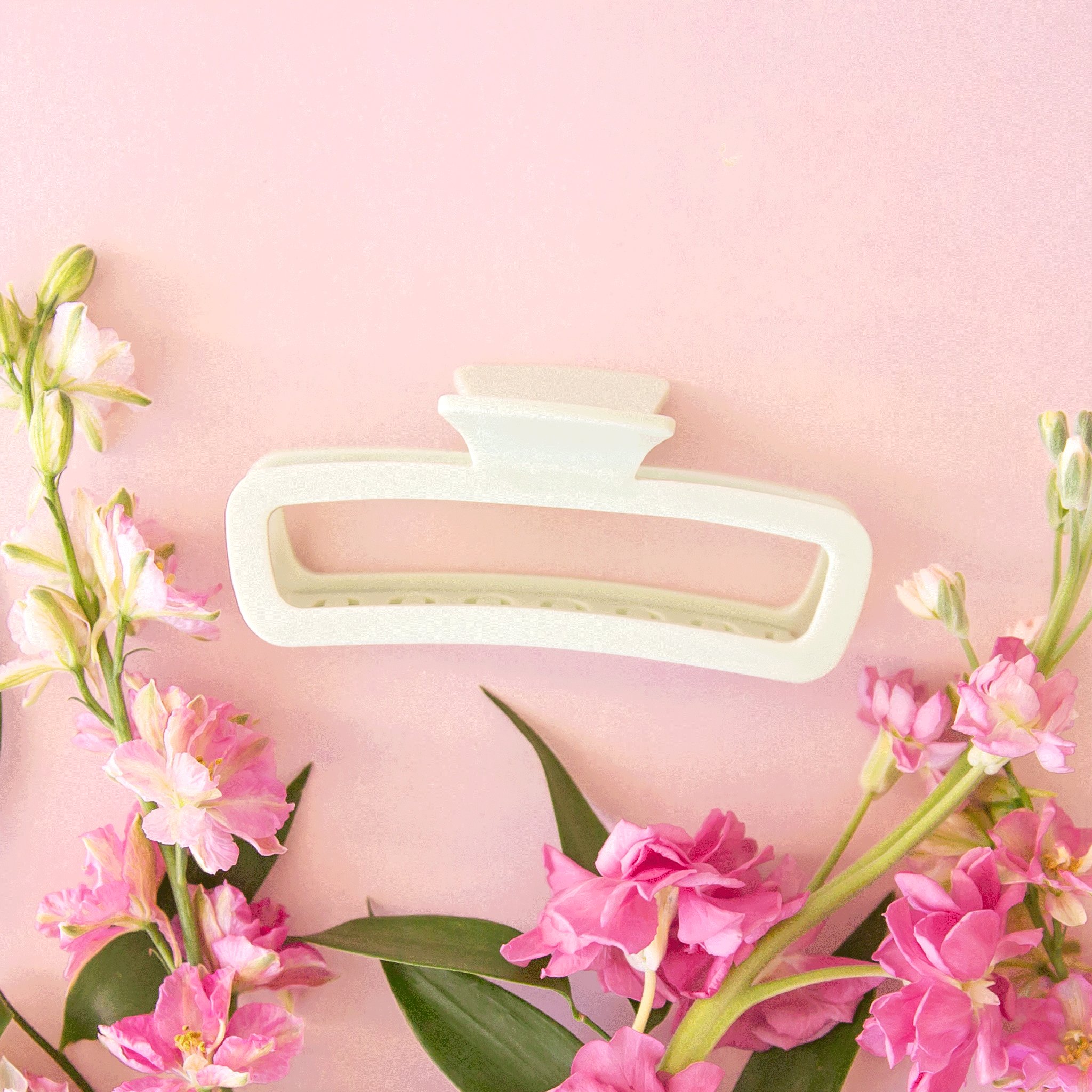 On a pink background is a rounded rectangle hair claw clip in mint green shade.