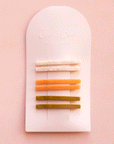 On a white packaging is six bobby pin clips in three different colors. From top to bottom is an ivory shell shade, mango orange, and olive green shade.