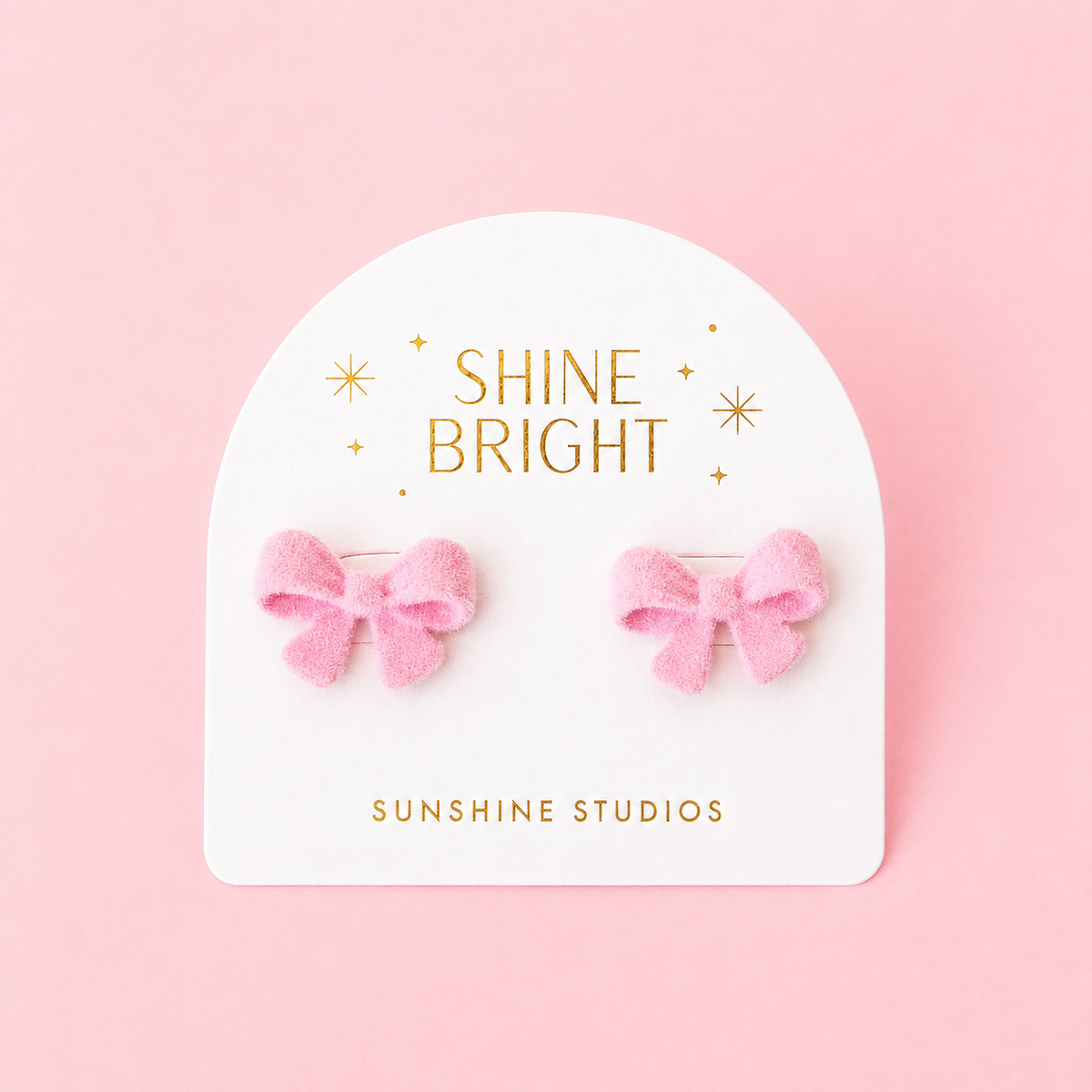 flocked pink bow shaped earrings on a white backer card.