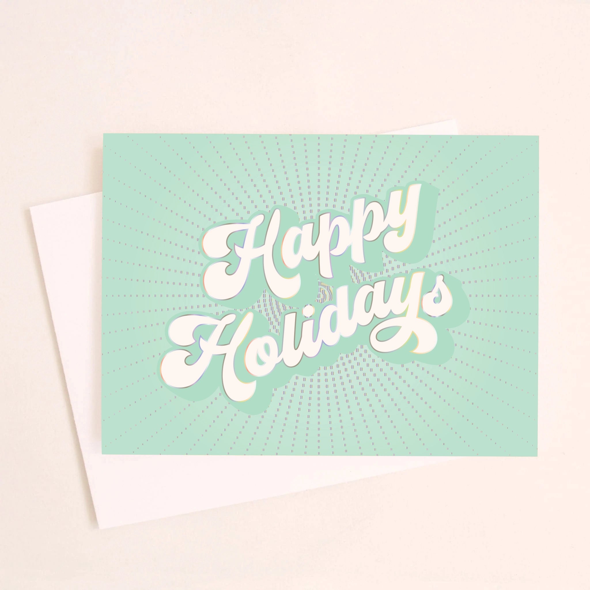 On an ivory background is a teal holiday greeting card with white text that reads, "Happy Holidays" along with a coordinating white envelope.