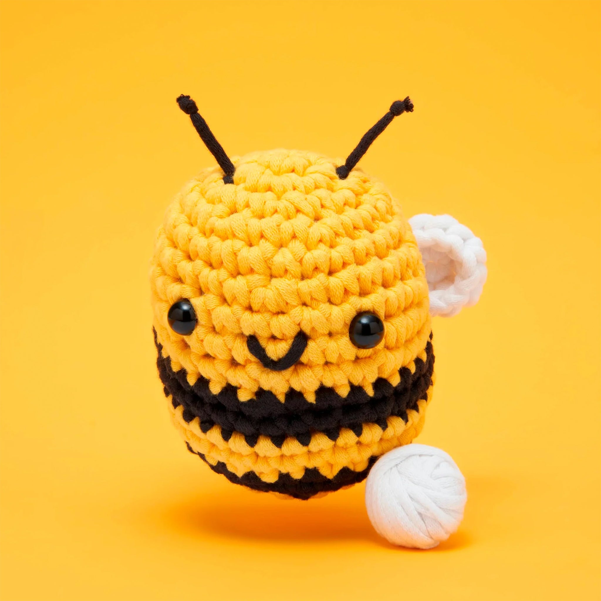 A crochet kit that creates a yellow and black bee with a smiling face and adorable wings. 