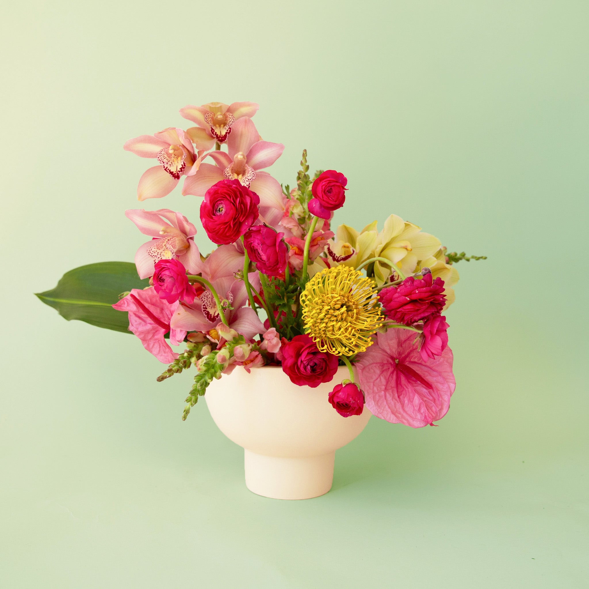 A ceramic pedestal planter and a flower on a light green background