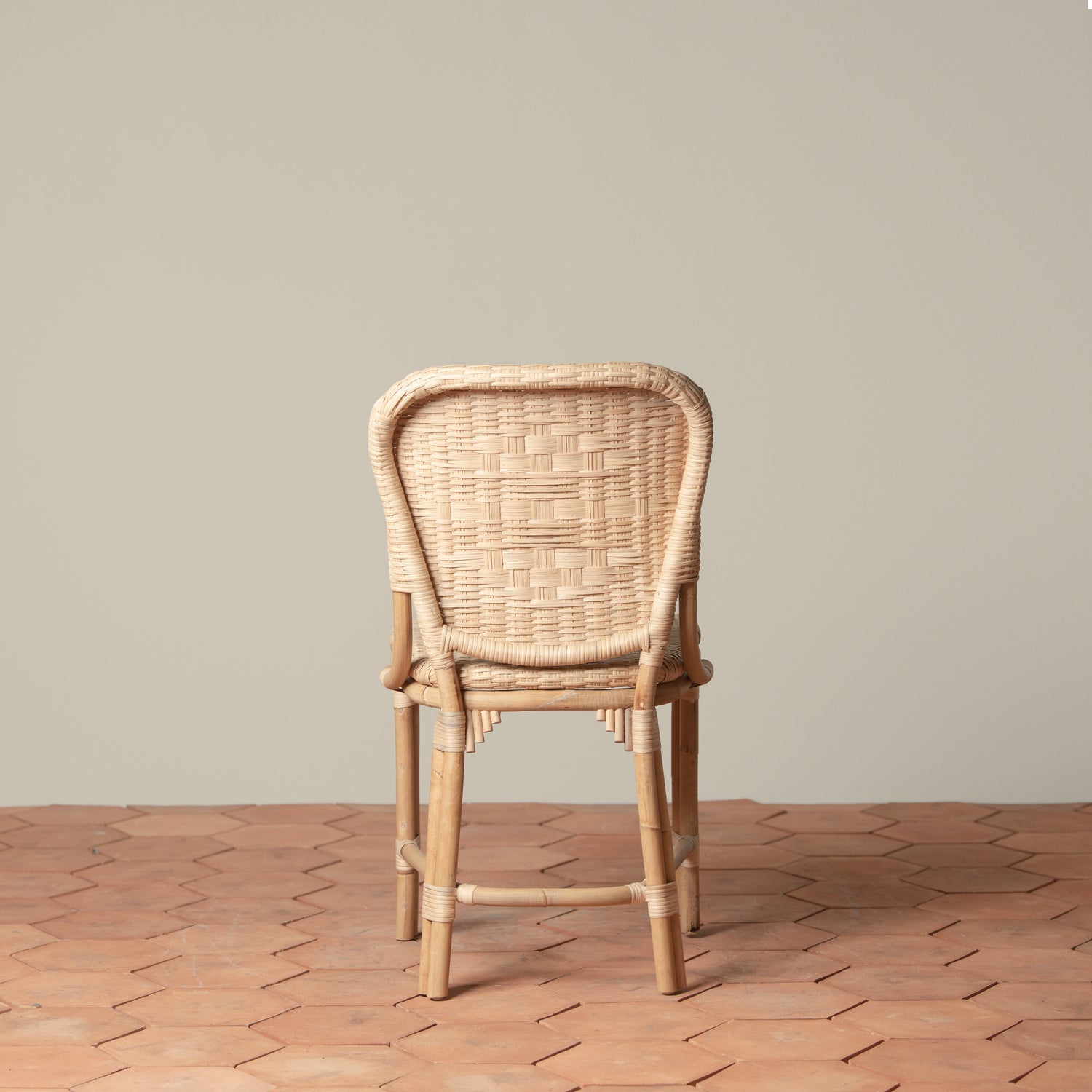 On an ivory background is a rattan chair with a woven rattan seat and backrest.