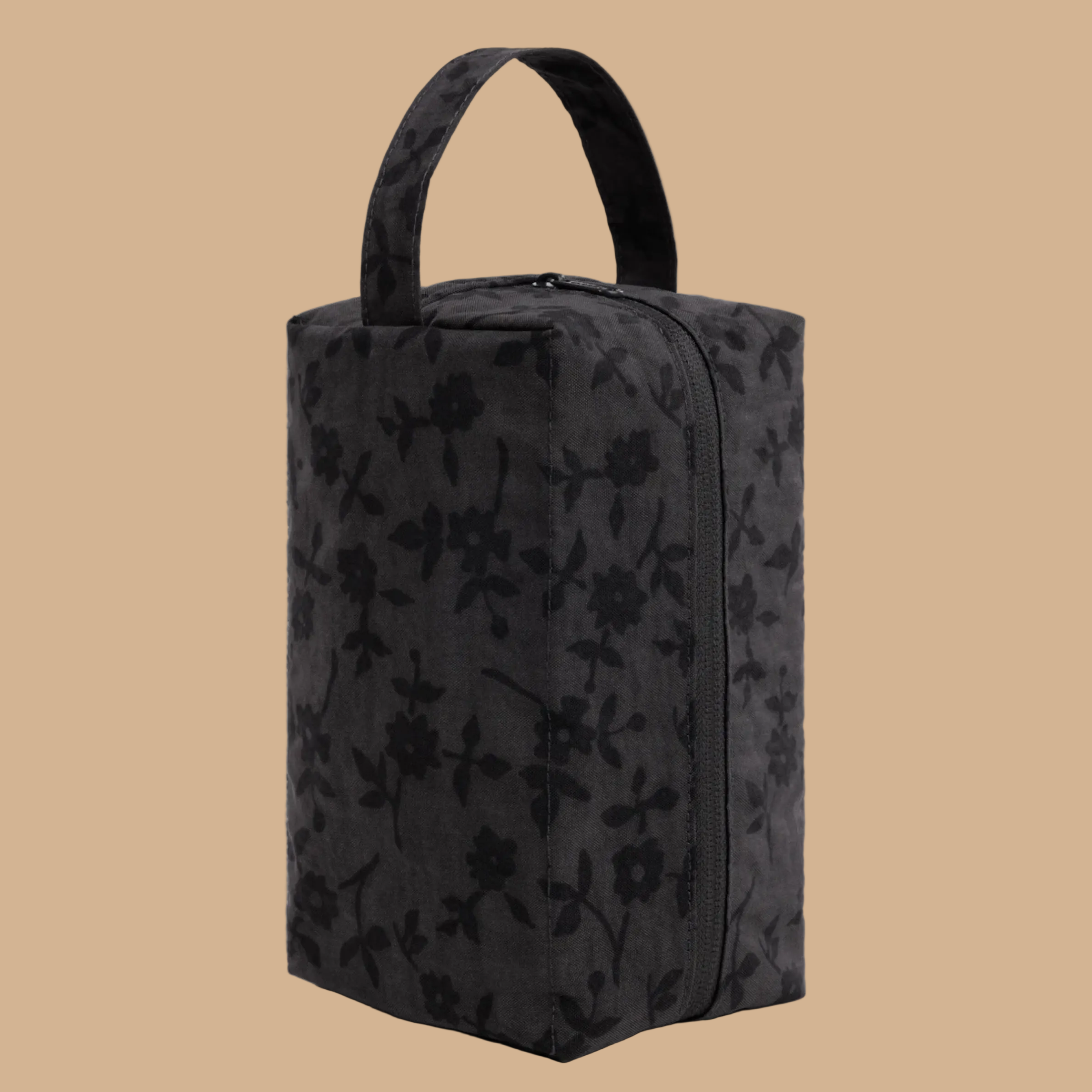 A black rectangular zippered pouch or bag with a top handle, featuring an all-over tonal floral pattern, shown against a light gray background.