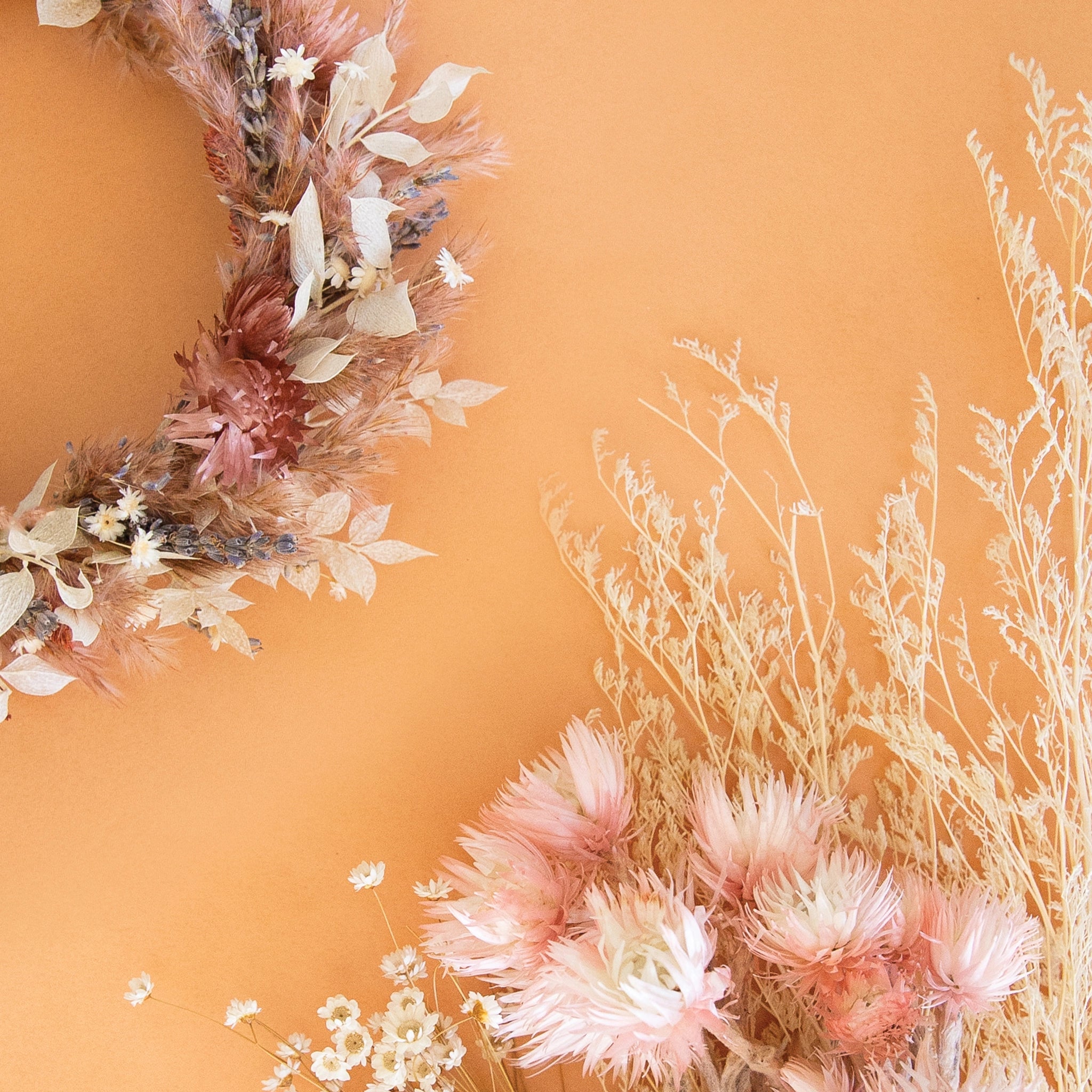 On an orange background is dried florals alongside a flower crown of florals. 