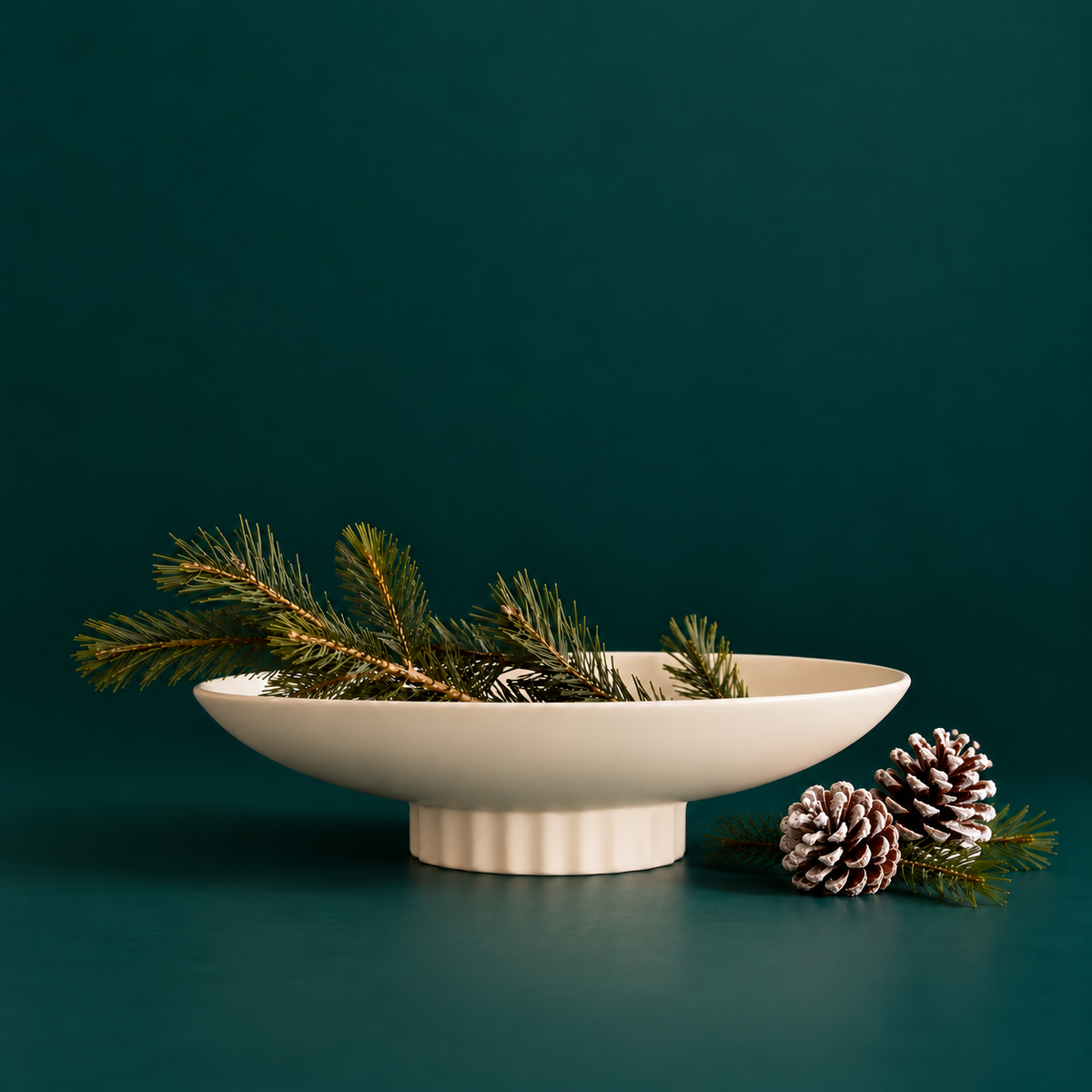 a white ceramic bowl holding a minimal pine branch arrangement. 