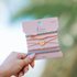 Hand holding a package of hair ties with a blurred green background