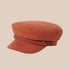 A terracotta colored fiddler cap with rope detailing. 