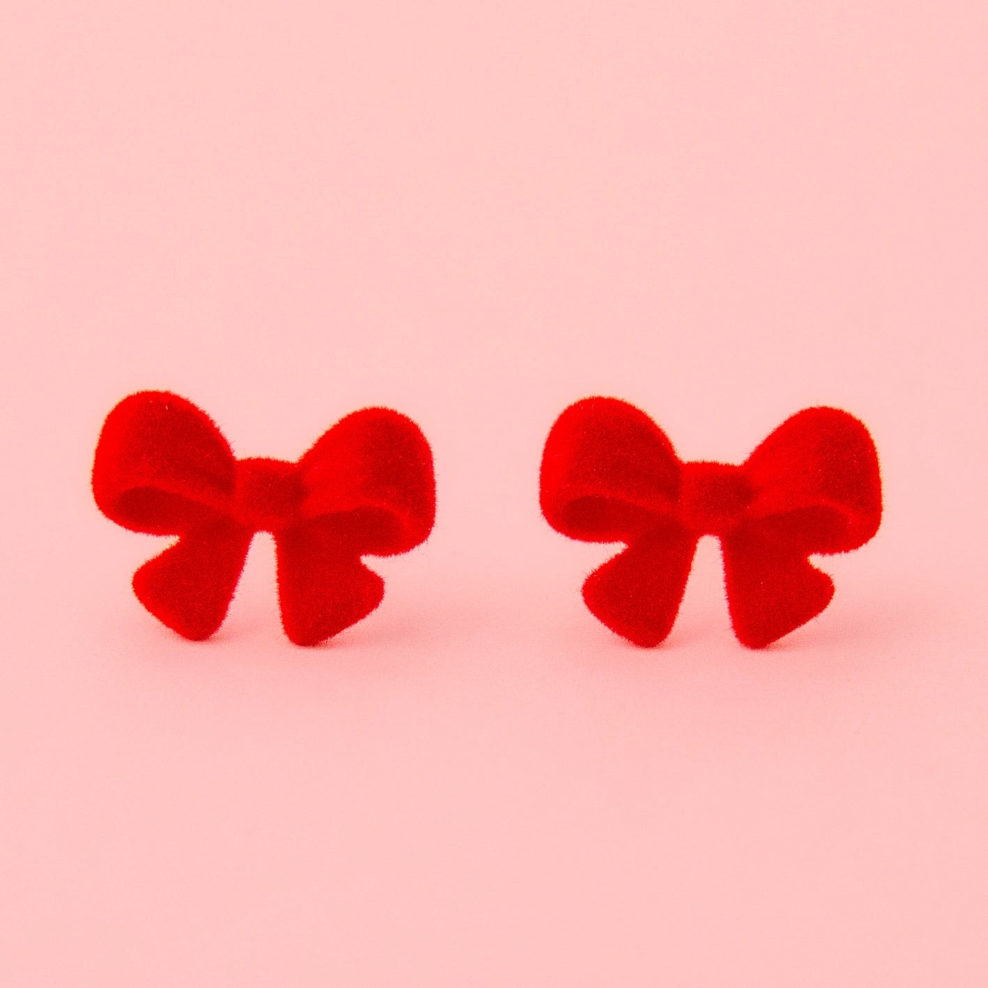 A pair of flocked red bow earrings.