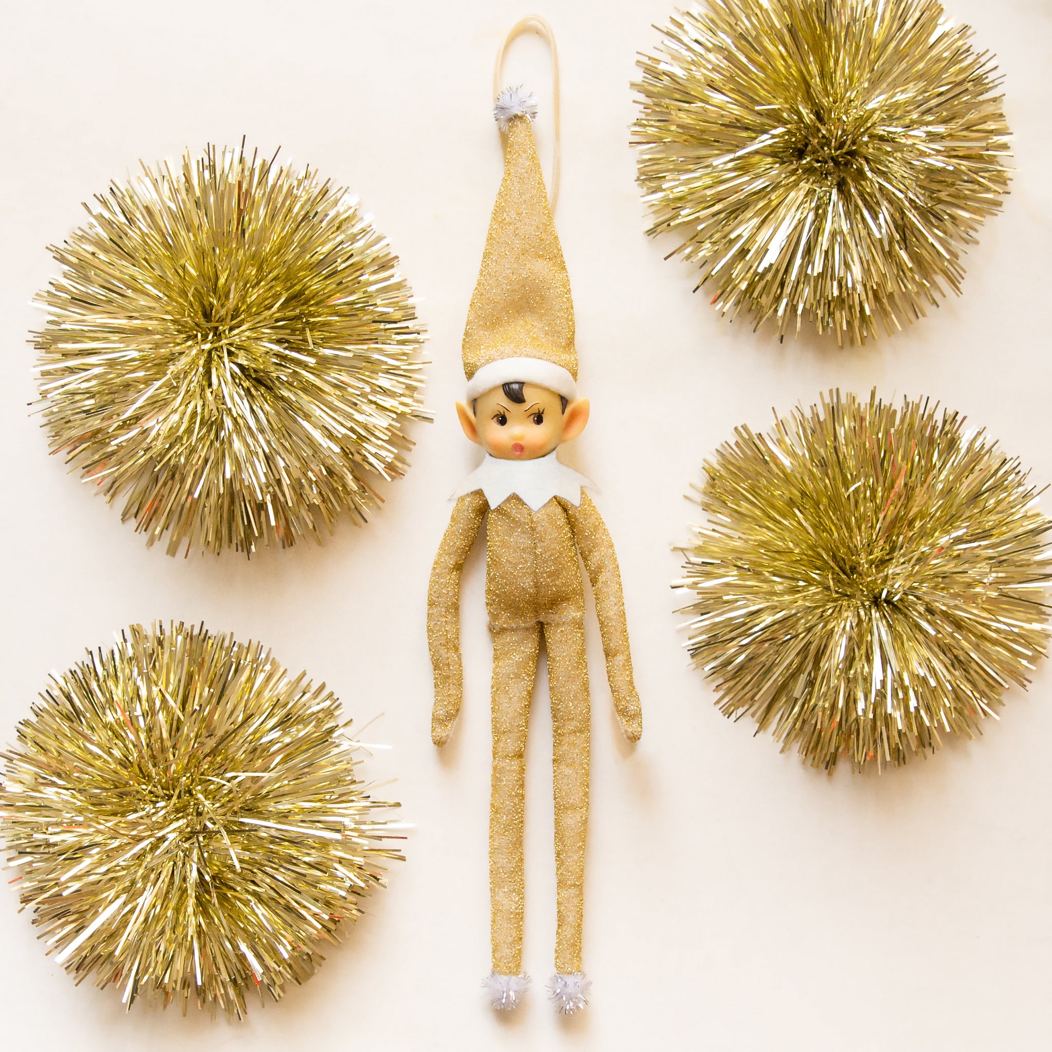 A gold sparkle elf shaped ornament with long limbs. 