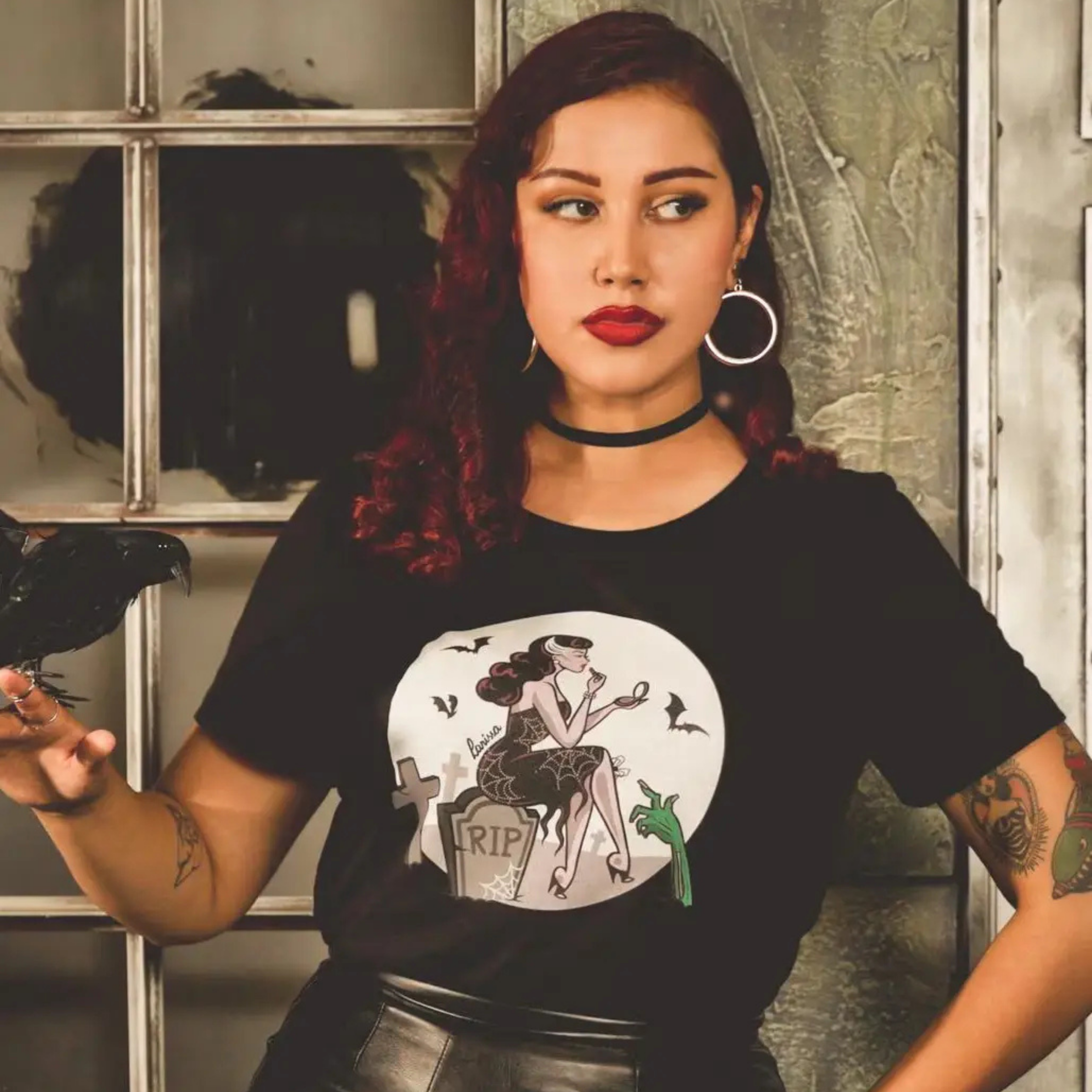 a model wearing a black tshirt with halloween tombstone design. 