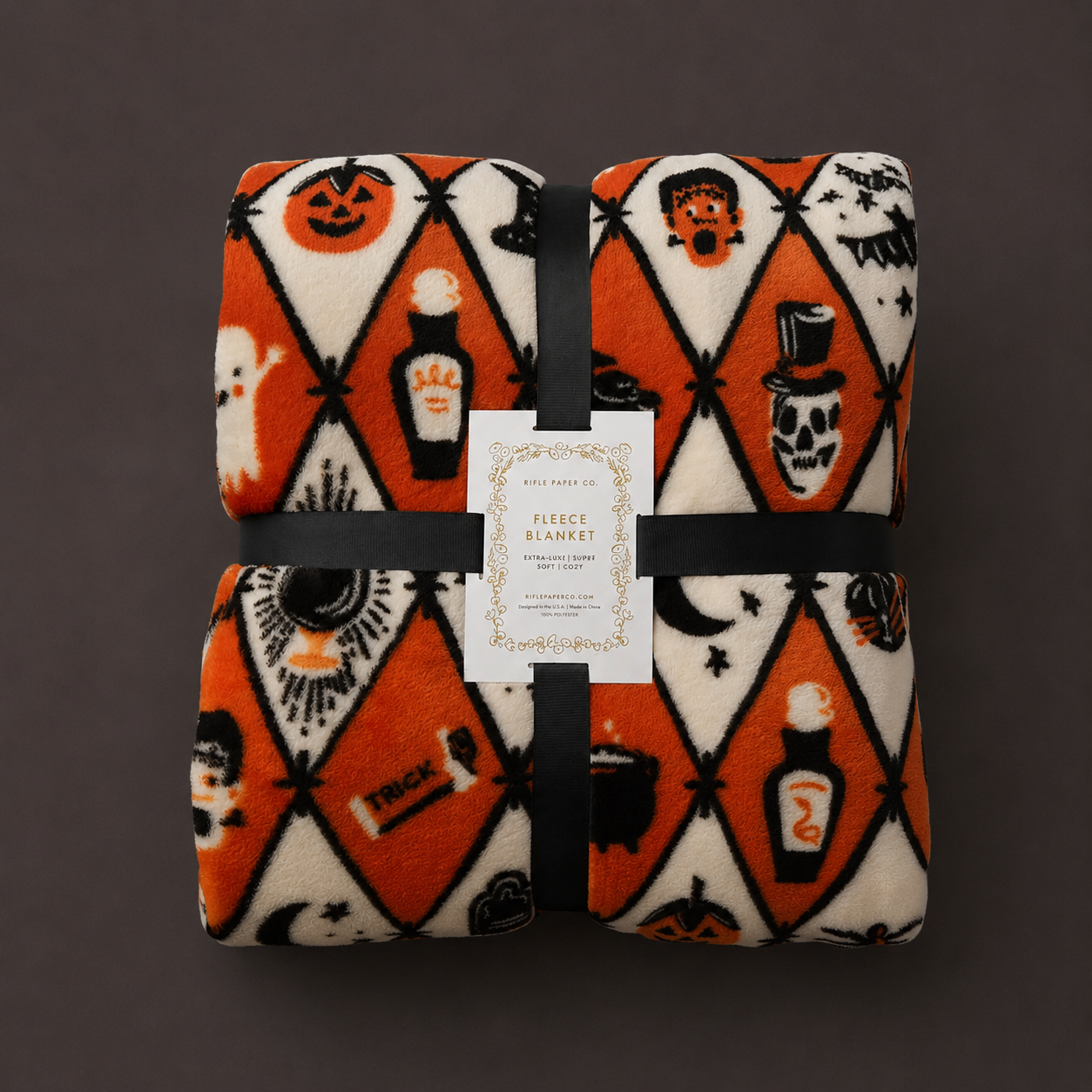 An orange, ivory and black diamond pattern fleece blanket with Halloween themed graphics. 