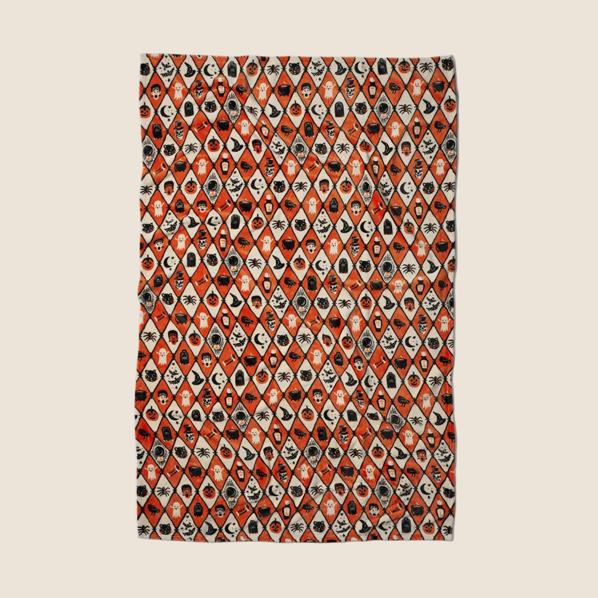 An orange, ivory and black diamond pattern fleece blanket with Halloween themed graphics. 