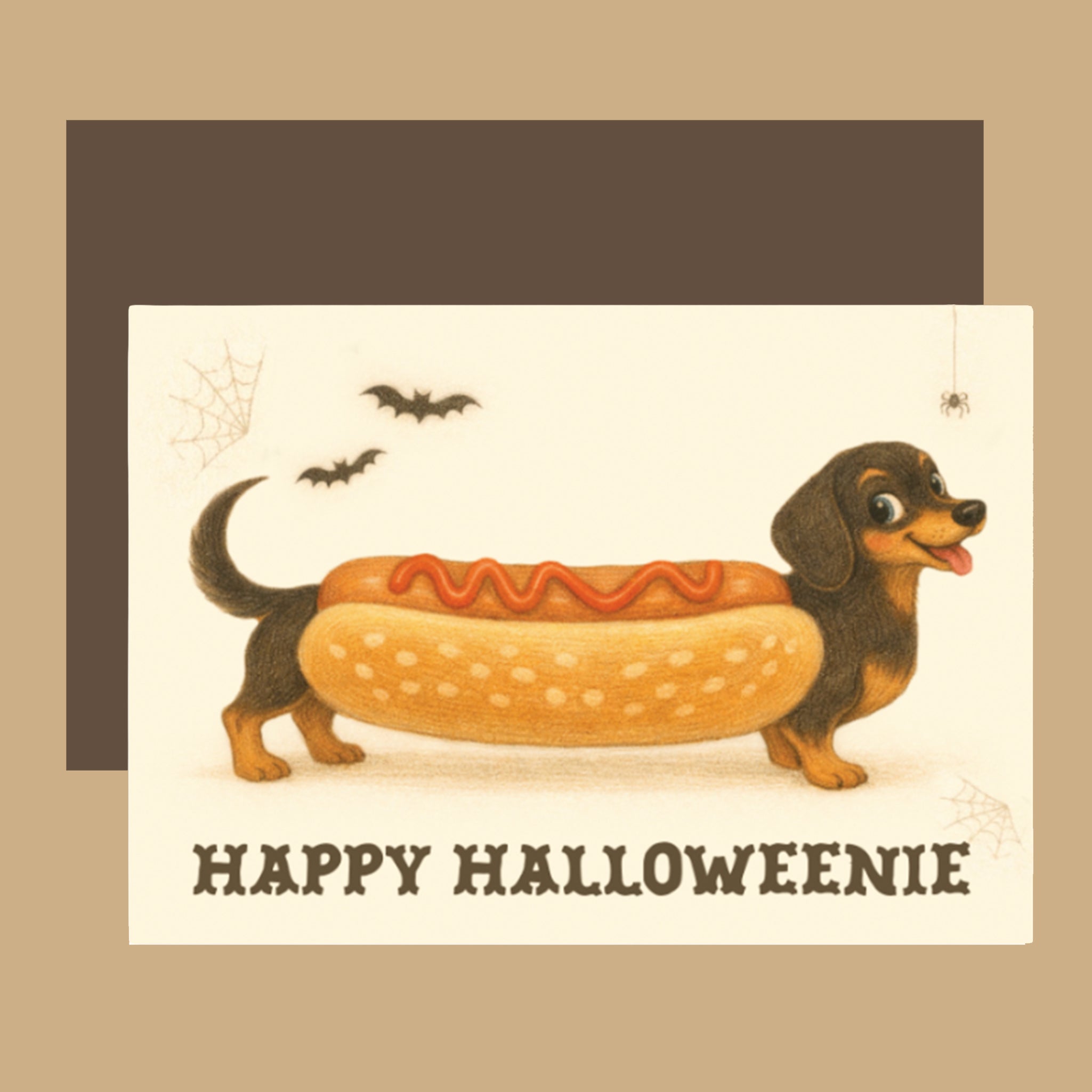 A Halloween greeting card featuring a dachshund dressed as a hot dog with ketchup, shown with a dark brown envelope behind it on a beige background.