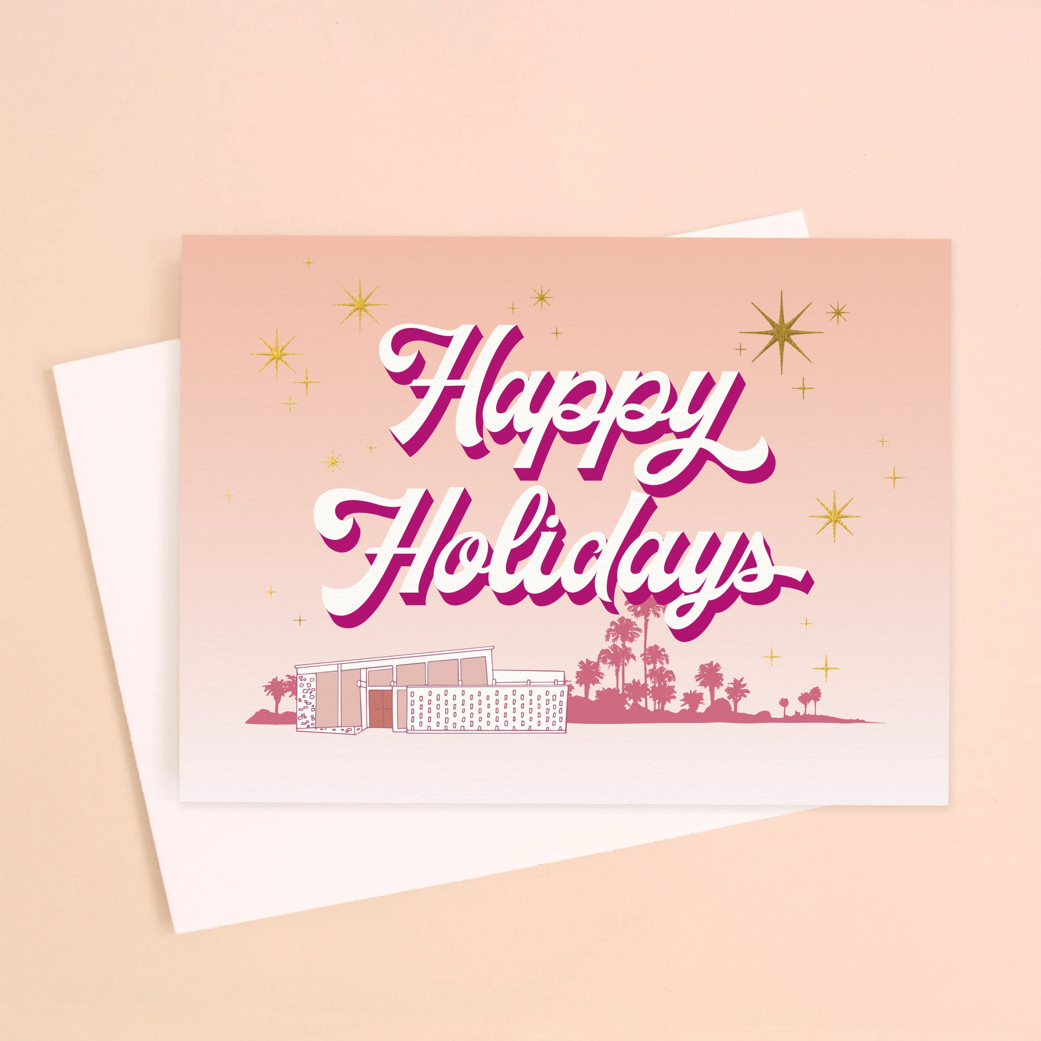 A peachy pink card with a pink Palm Springs midcentury home graphic and pink text that reads, 'Happy Holidays'. 