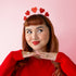 A headband hair accessory with red glitter hearts along the top. 