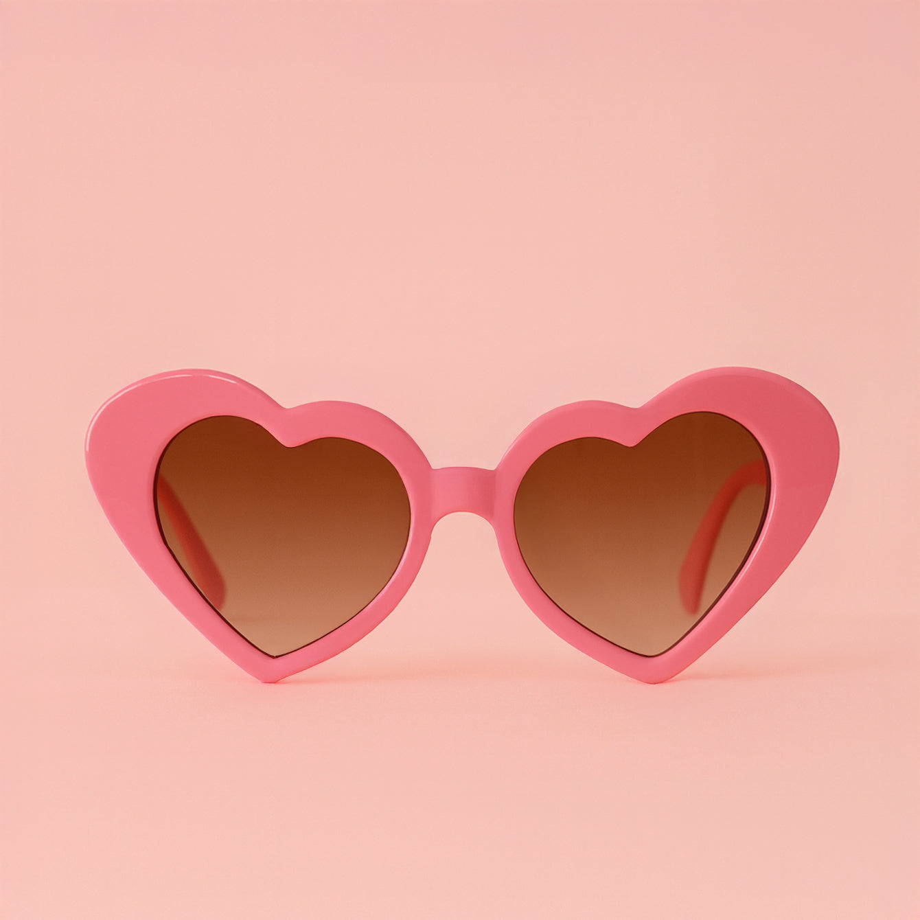 A pink pair of heart shaped sunglasses. 