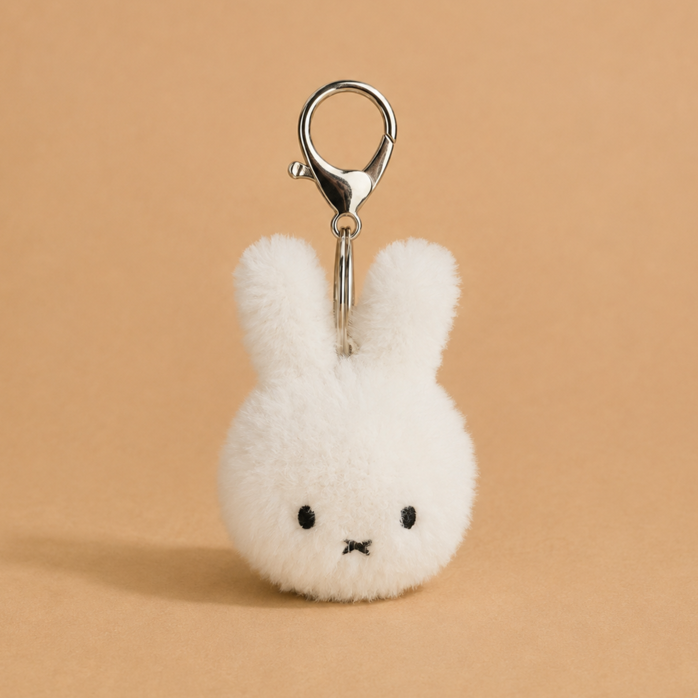 an off white fuzzy miffy character keychain