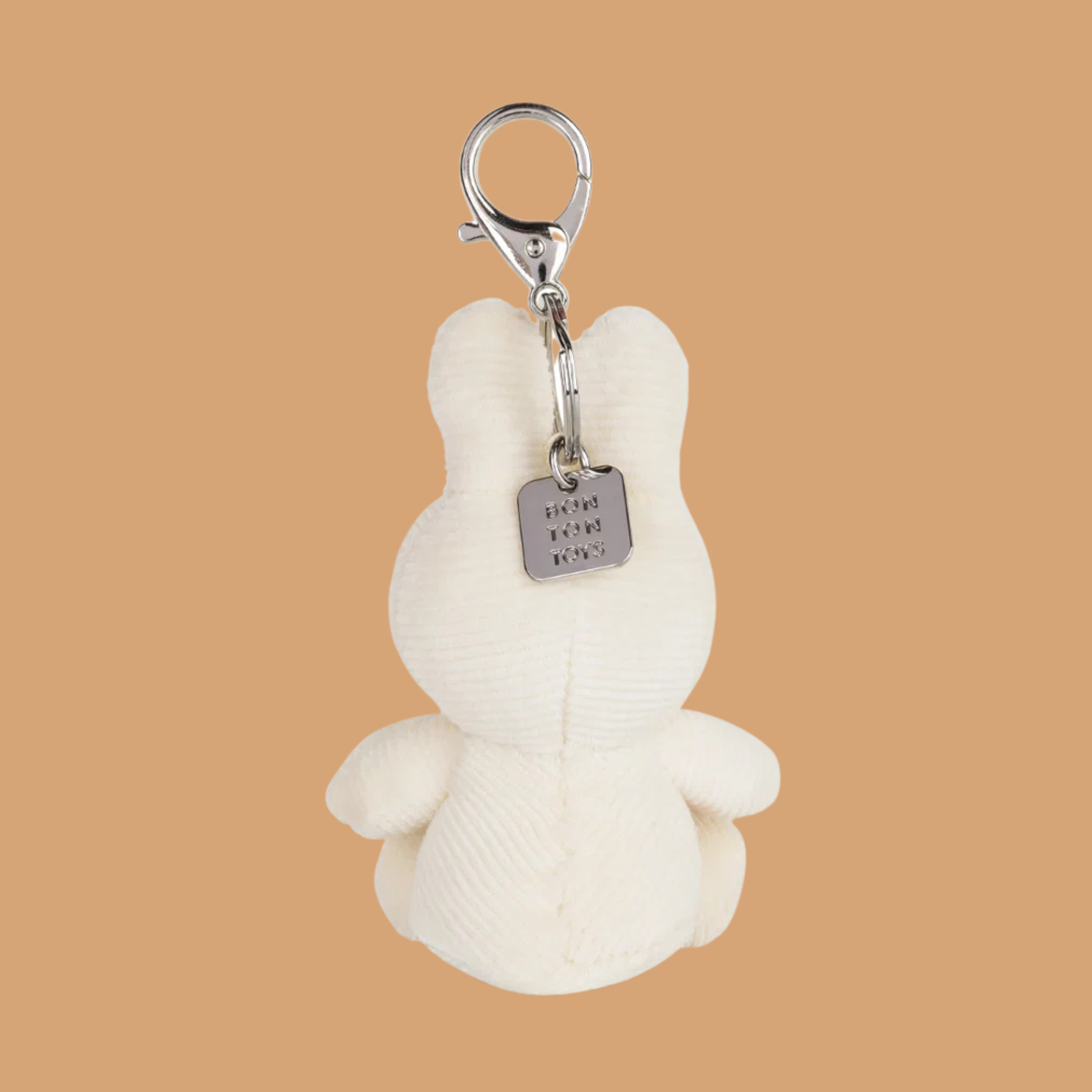 a white keychain with a plush miffy character with a rainbow design on its stomach. 