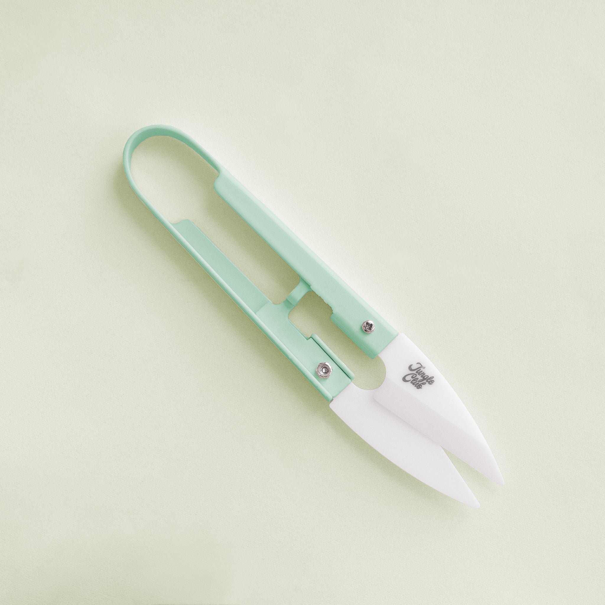 On a light green background is a pair of mint green mini plant shears with small text on the clippers that reads, "Jungle Club".