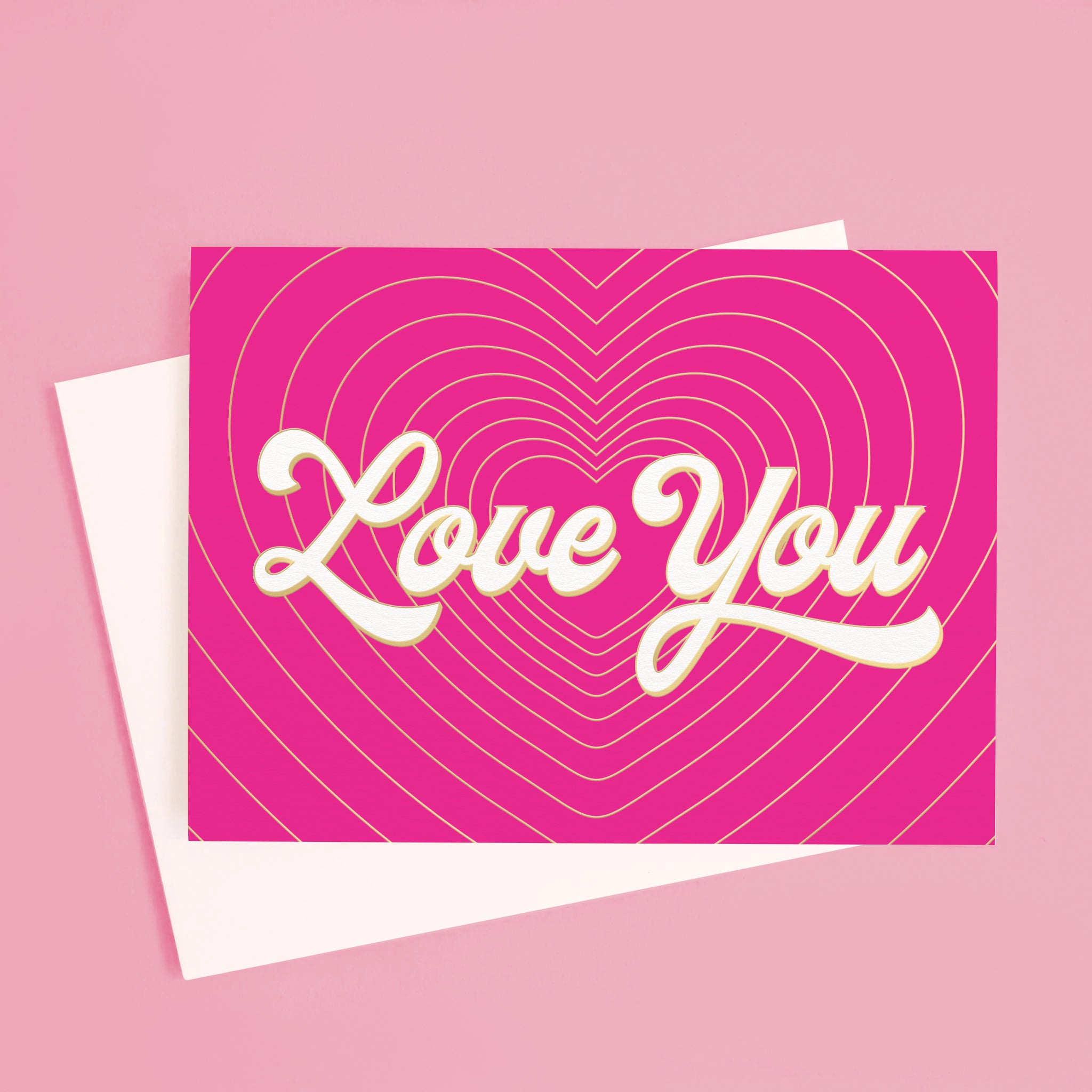 On a pink background is a hot pink card with gold heart shaped lines with ivory text in the center that reads, &quot;Love You&quot;. 