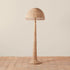 A neutral rattan floor lamp with a bamboo wrapped post and a woven domed lampshade. 