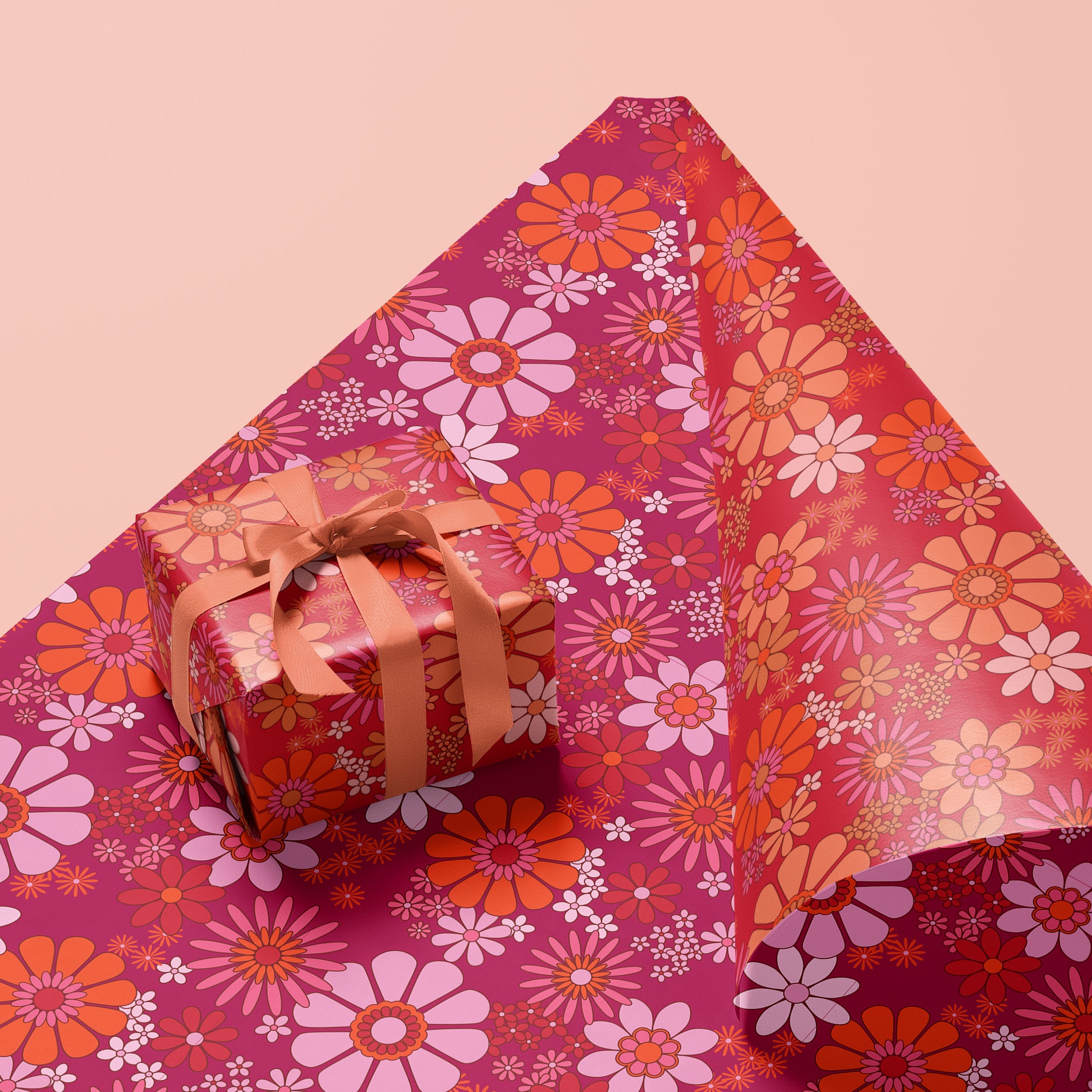 On a pink background is a hot pink and orange floral gift wrap.