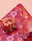 On a pink background is a hot pink and orange floral gift wrap.