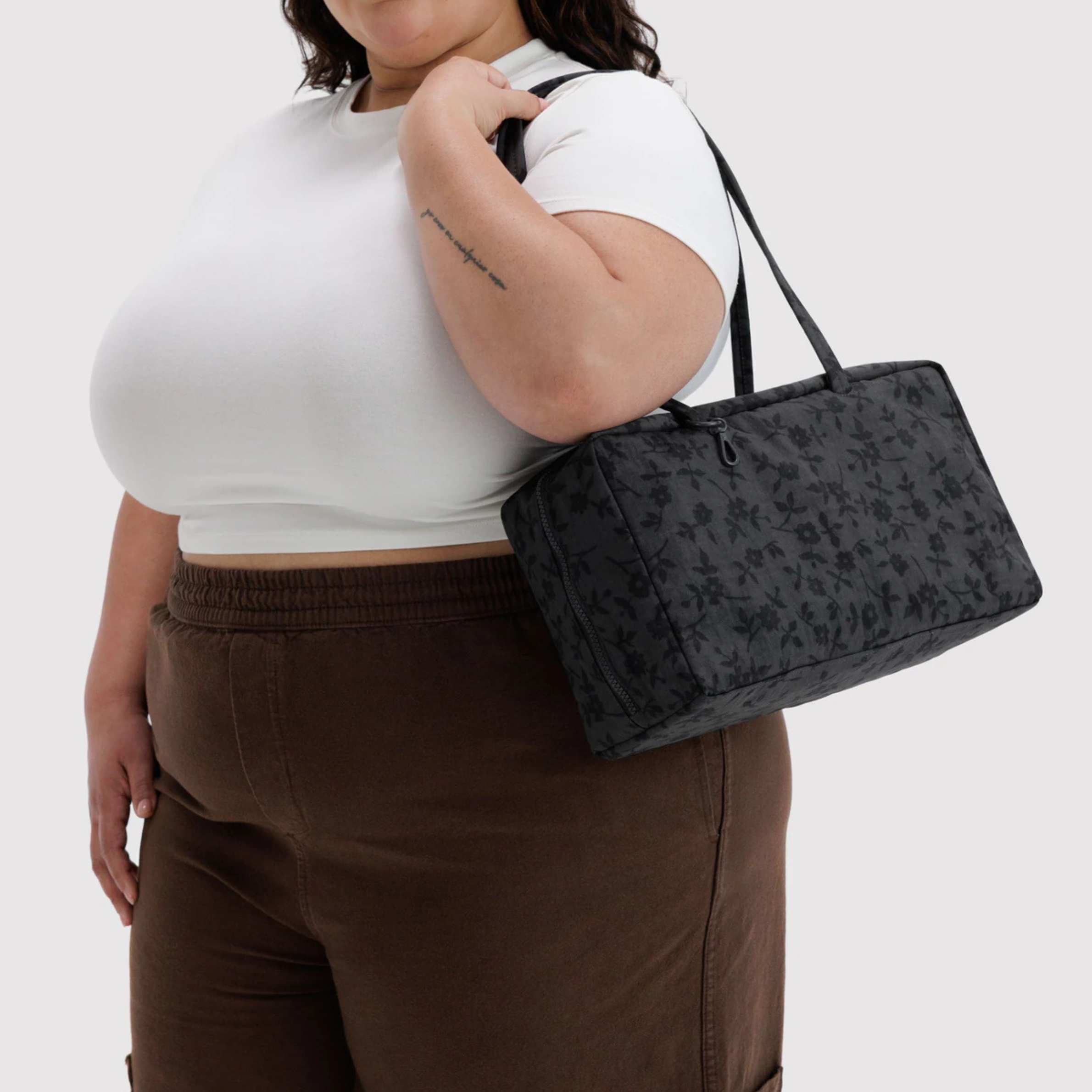 A black rectangular tote bag with a subtle floral pattern, featuring dual top handles and a top zipper closure