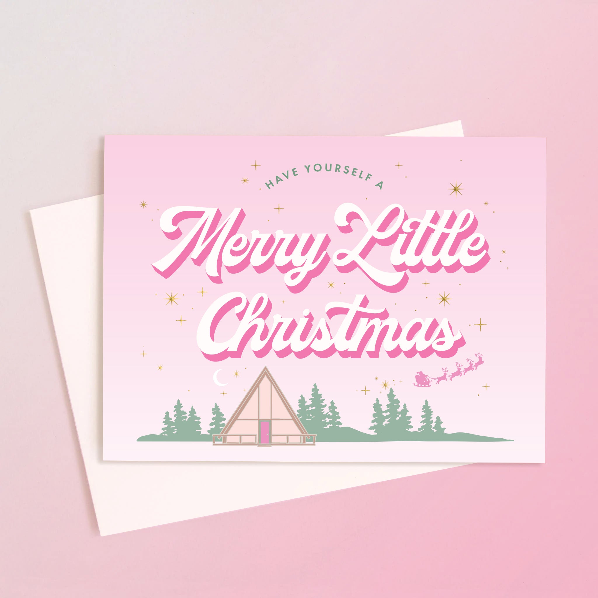 A light pink card with a retro A-frame cabin graphic with text above that reads, 'Have Yourself A Merry Little Christmas'. 