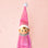 A pink elf ornament. The elf has a tinsel collar and pompom on its hat. 
