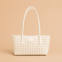 a white woven shoulder bag. 