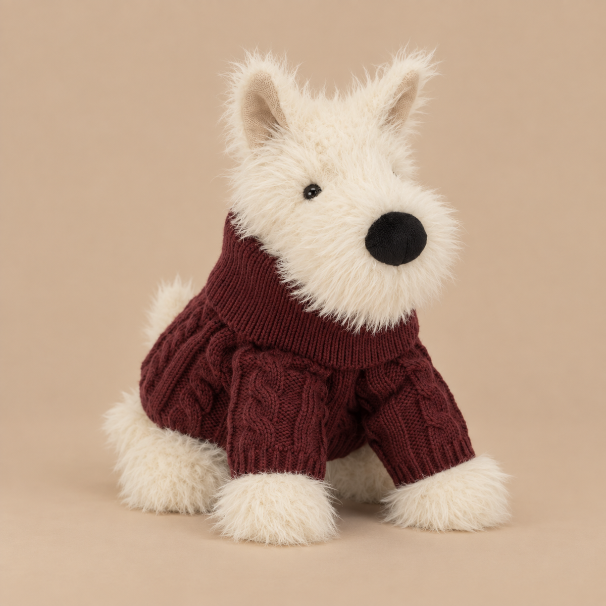 a white scottie dog plush toy wearing a rusty red colored sweater.