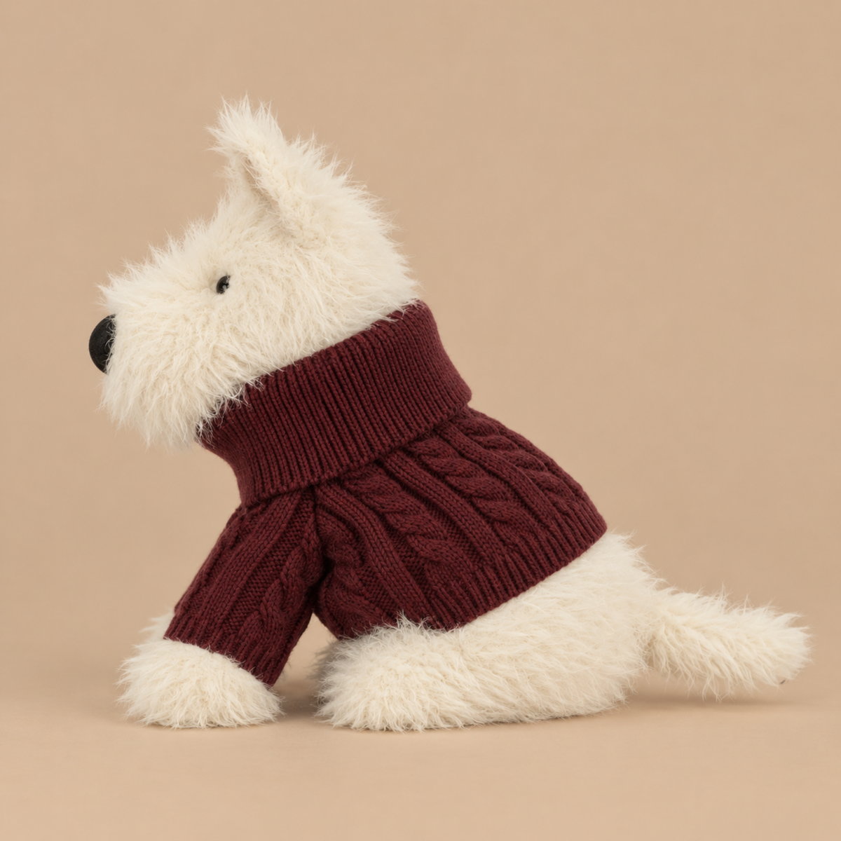a white scottie dog plush toy wearing a rusty red colored sweater.
