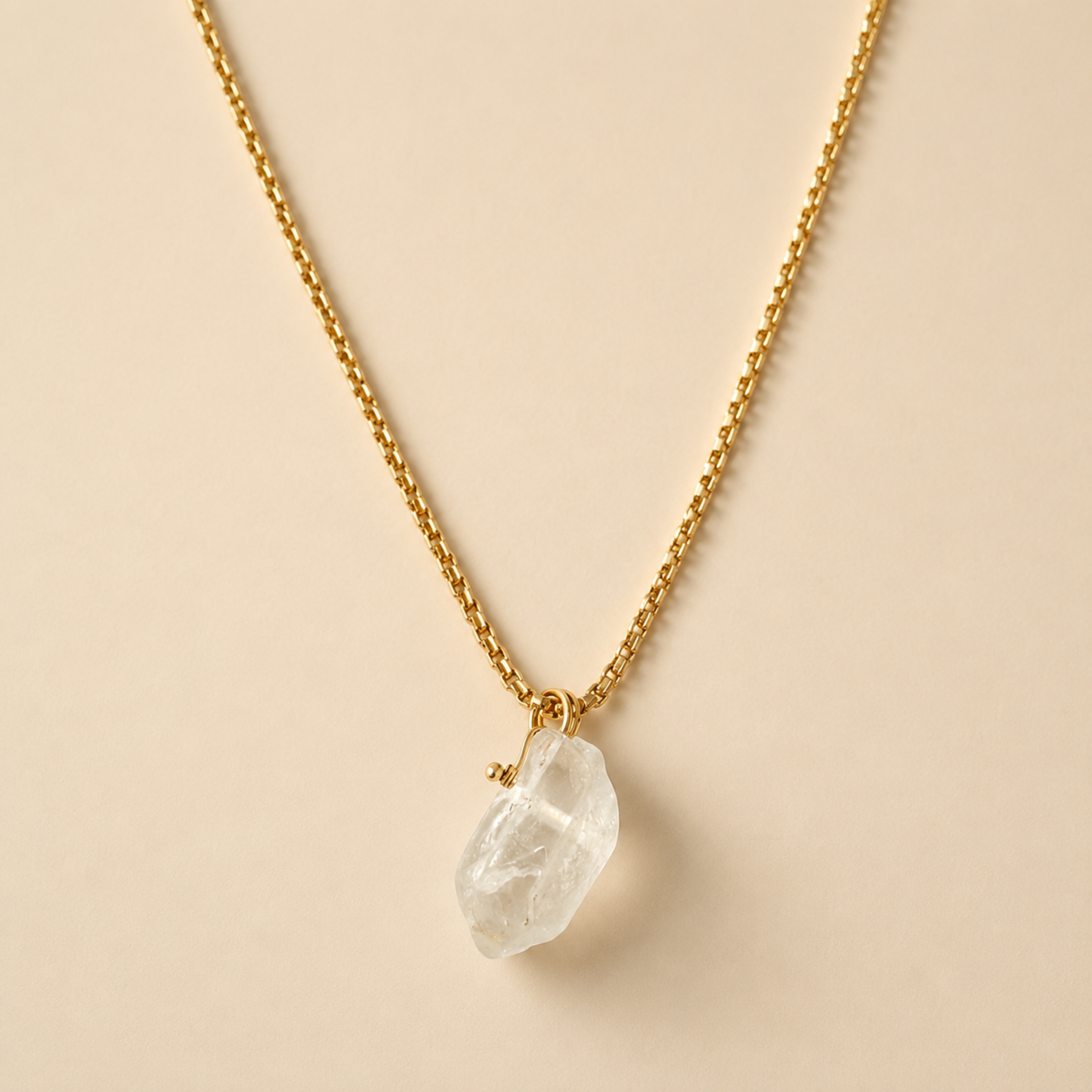 a gold necklace with a clear quartz stone in the center as a pendant. 