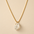 a gold necklace with a clear quartz stone in the center as a pendant. 